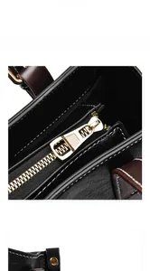 Detalle de bolso de cuero negro con cremallera dorada y costuras blancas de precisión