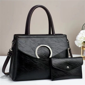 Macro shot of textured black leather handbag surface with metallic buckle and fine stitching