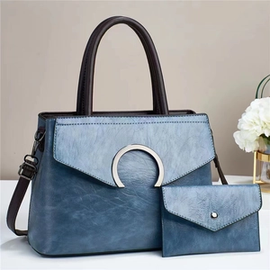 Detail view of contrast color tote bag and matching pouch in textured blue leather