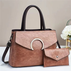 Close-up of brown textured leather handbag set with silver buckle and matching small pouch