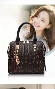 Detail of dark brown leather tote featuring ALDALD pattern with cat charm and tassel