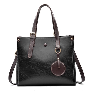 Grand sac cabas en cuir texturé noir avec anses marron et détails dorés brillants