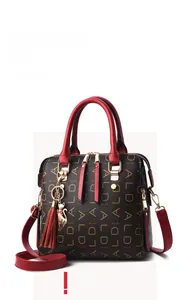 Close-up of wine red PU leather handle, cat charm, and monogram print on large handbag