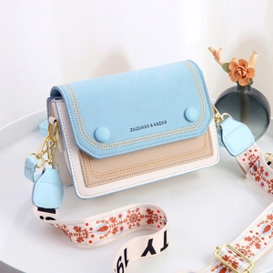 Detail of multi-color crossbody bag with embroidered wide strap and gold hardware