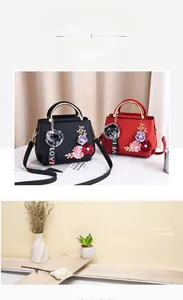 Détail du sac à bandoulière avec broderie florale, pompon et sangle LOVE