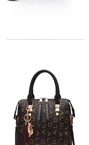 Detail of black PU leather handbag featuring gold cat charm and red tassel decoration
