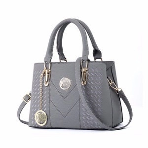 Dark grey faux leather tote bag with V-shaped stitching and golden metal logo on white background