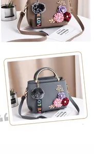 Détails des accents floraux et du pompon en peluche sur un sac en cuir grainé