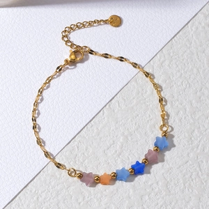 Detail of gold stainless steel bracelet with five colorful matte star-shaped charms