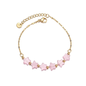 Detailed macro view of gold stainless steel star bracelet with pink cat eye beads