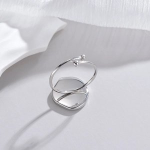 Macro shot of silver minimalist open ring with irregular mirror finish and geometric metal balls