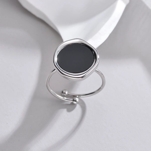 Detail of adjustable silver ring featuring a round black inlay and sphere accents