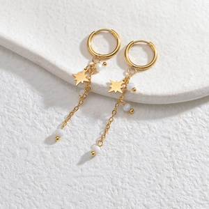 Minimalist 14K gold-plated star tassel earrings with white beads on a textured surface