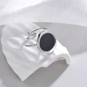 Minimalist silver open ring with irregular black shell inlay on white fabric