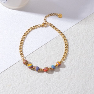 Detail of gold-plated stainless steel Cuban link bracelet with vibrant striped beads