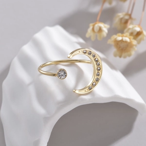 Bague dorée élégante en forme de croissant de lune et diamant sur un support blanc texturé