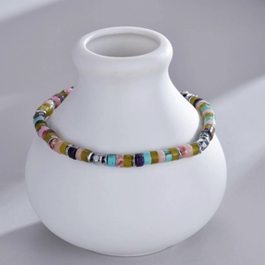Detail of colorful bohemian stone bead bracelet with silver spacers on white ceramic vase