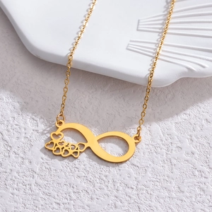 Minimalist gold infinity necklace with hollow heart details on white ceramic tray