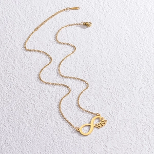 Elegant gold infinity necklace with hollow heart pendant on a white textured background