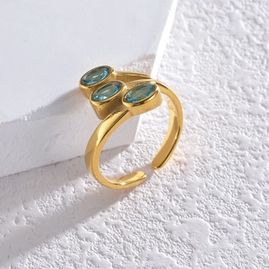 Macro detail of gold-plated ring featuring three sky blue oval stones in bezel setting