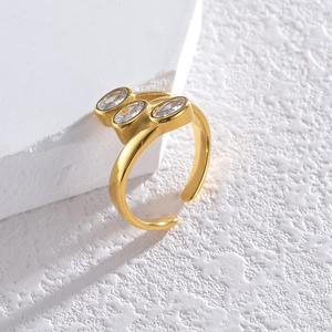 Detail of gold oval zircon ring with three-stone inlay design on a textured stone