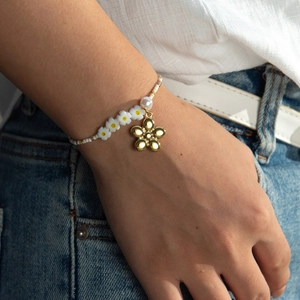 Bracciale di perline margherita con ciondolo floreale dorato indossato da modella