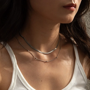 Double layered silver snake chain necklace with bead details on a model