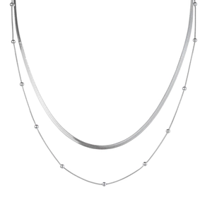 Close-up of a double-layered silver snake chain and beaded necklace in a minimalist design