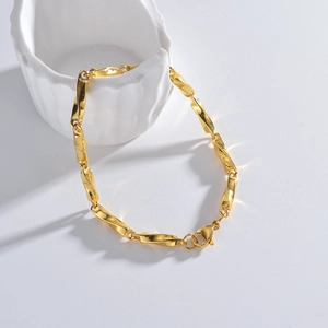 Détail d'un bracelet gourmette torsadé doré Mobius suspendu à une tasse en céramique