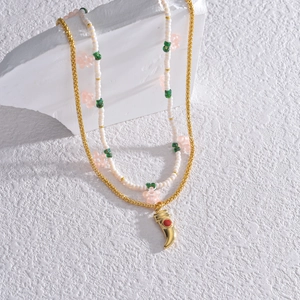 Collier double rang perlé avec pendentif corne dorée et pierre rouge sertie