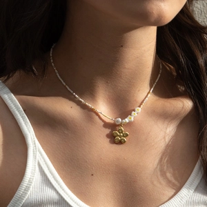 Colorful floral beaded necklace with gold petal pendant and pearls on model neck