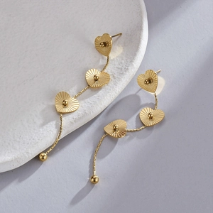 Détail de boucles d'oreilles cœur en acier inoxydable doré 14K sur céramique blanche