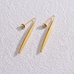 Vue détaillée de longues boucles d'oreilles dorées en forme de cône poli sur blanc