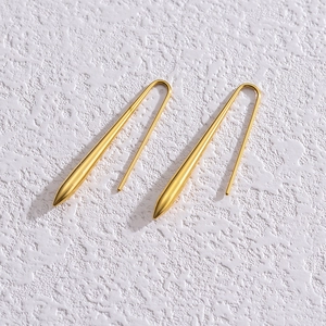 Gros plan de boucles d'oreilles gouttes dorées au design minimaliste et épuré