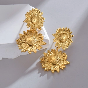 Artistic gold sunflower earrings with layered petals on a minimalist stone display