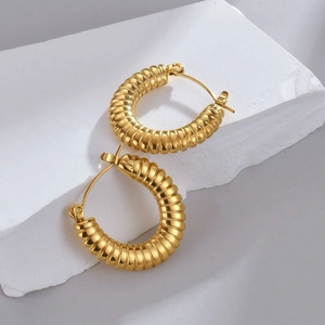 Dettaglio di orecchini a cerchio in oro 18K con design a spirale stile croissant