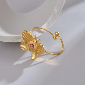 Macro detail of golden butterfly open ring with pink zircon and textured wings