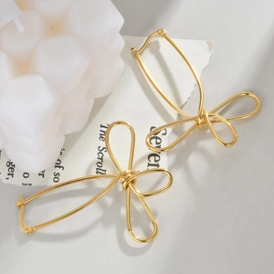 Vue détaillée de boucles d'oreilles dorées en forme de nœud sur un présentoir élégant