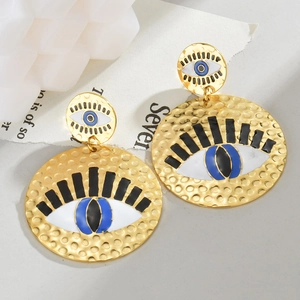 Détail des boucles d'oreilles œil porte-bonheur dorées avec texture martelée et émail
