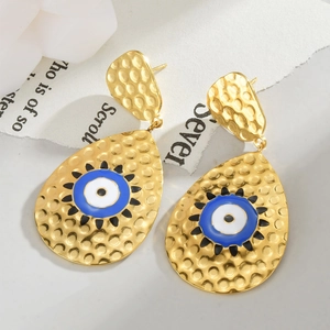Vue macro de boucles d'oreilles goutte dorées avec émail œil bleu et texture martelée