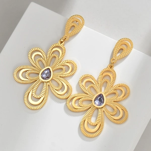 Boucles d'oreilles fleurs dorées ajourées avec pierre violette sur fond géométrique blanc