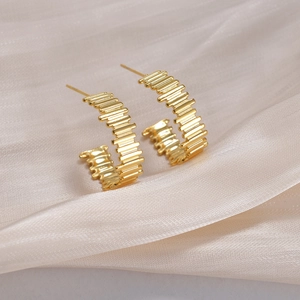 Detailed view of gold geometric hoop earrings with ribbed texture on champagne silk