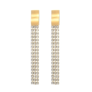 Détail de boucles d'oreilles dorées avec franges en zircon et clous en métal brossé