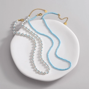 Double-layered beaded necklace with faux pearls and light blue beads on a white tray