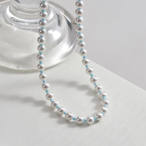 Vintage layered pearl necklace with light blue beads on a textured white background