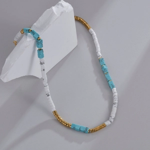 Detailed shot of beaded necklace with blue turquoise and white marble stones on stone