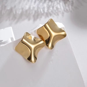 Detail von unregelmäßigen hohlen Goldquadrat-Ohrringen mit polierter skulpturaler Textur
