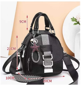 Close-up of black leather backpack with size 21cm, star pendant and striped shoulder strap