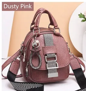 Detail of dusty pink backpack with litchi texture and metallic star charms on display