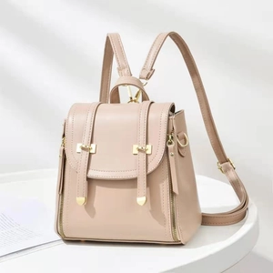 Detail of nude soft faux leather backpack featuring gold zippers and decorative straps